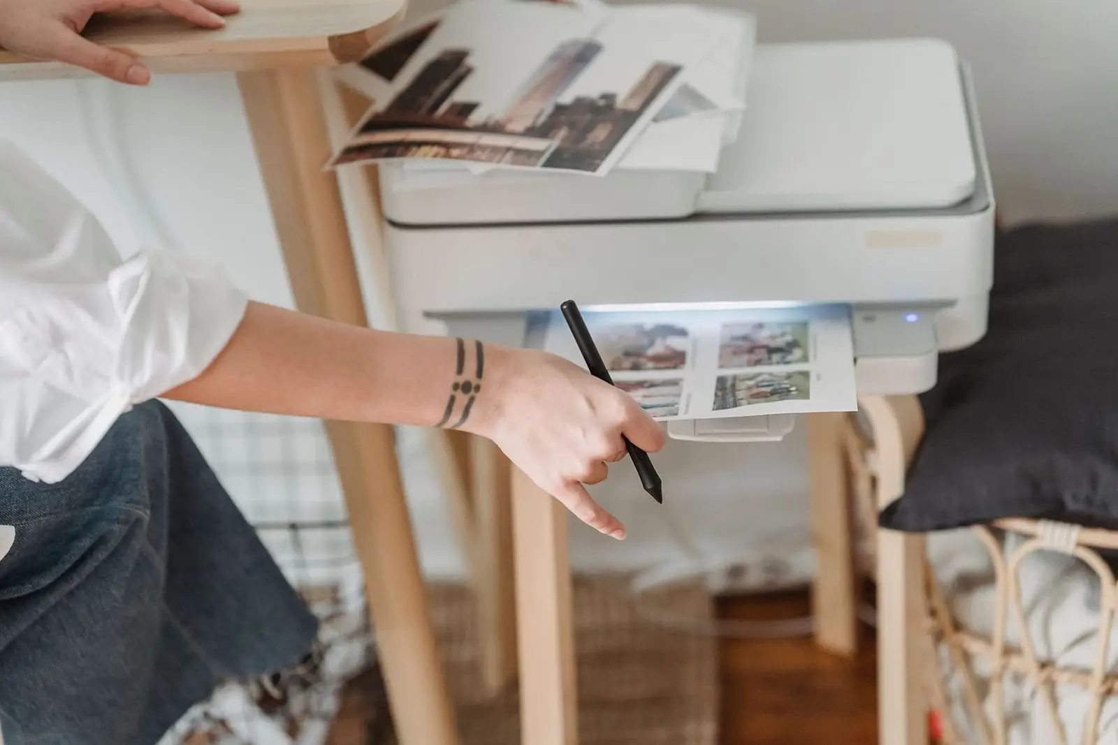 Hand reaching for a printed page coming out of a home printer and scanner